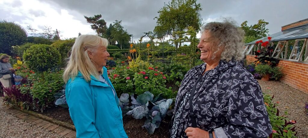 Image of two members chatting in garden setting