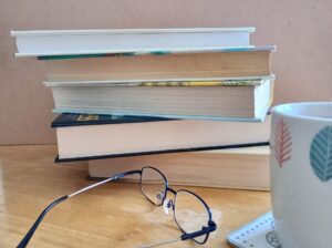 Stack of books with glasses and mug of tea